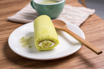 Roll cake with green tea on wooden table