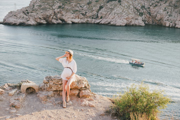 Young beautiful pregnant woman posing on a mountain near sea