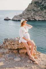 Fototapeta na wymiar Young beautiful pregnant woman posing on a mountain near sea