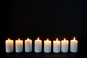 candles burning in darkness over black background