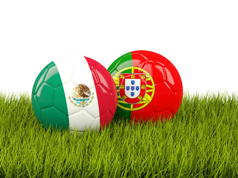 Two footballs with flags of Mexico and Portugal on green grass