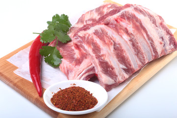 Raw pork ribs with herbs and spices on wooden board. Ready for cooking.