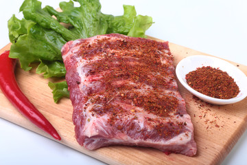 Raw pork ribs with herbs and spices on wooden board. Ready for cooking.