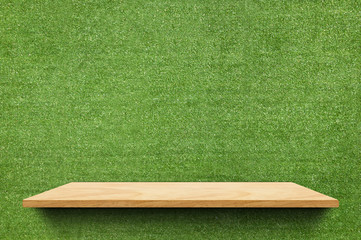 Empty wood board shelf at fake green grass wall background,Mock up for display or montage of...