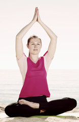 Fototapeta na wymiar Girl practicing yoga poses on beach