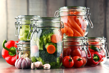 Jars with marinated food and organic raw vegetables