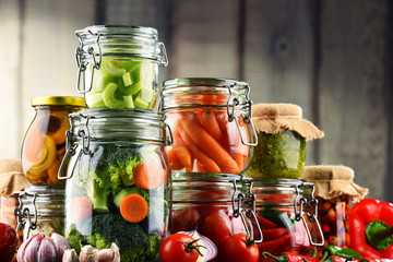Jars with marinated food and organic raw vegetables