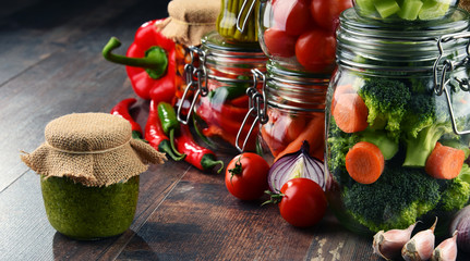 Jars with marinated food and organic raw vegetables
