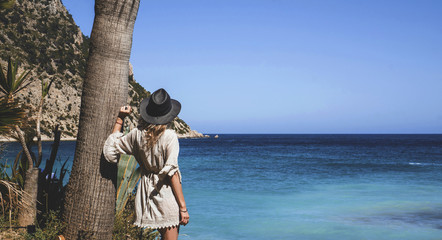 Girl with hat looking to the blue sea