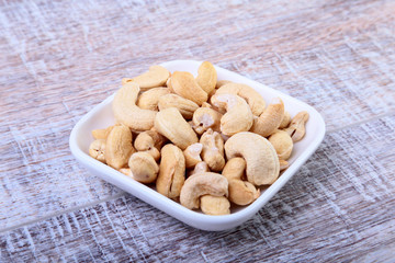 nuts cashews in white bowl on wooden background. Selective focus.