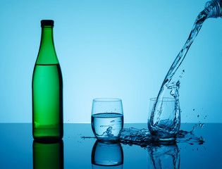 Bottle with creative splashing water in the glass