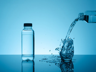 Bottle with creative splashing water in the glass