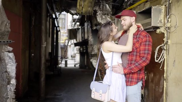 Young couple of hikers got lost in the courtyards of the old town. Stand and happily discussing what to do next. Girl with a fashionable bag on the shoulder.