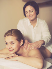 Obraz na płótnie Canvas Masseuse massaging shoulders of adult woman