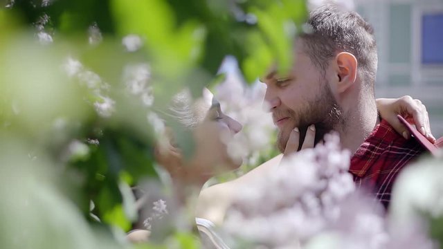 Beautiful young couple standing in the bushes close-up look at each other girl's hand stroking the beard of his men.