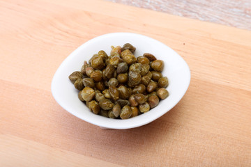 bowl with fresh capers on wooden table