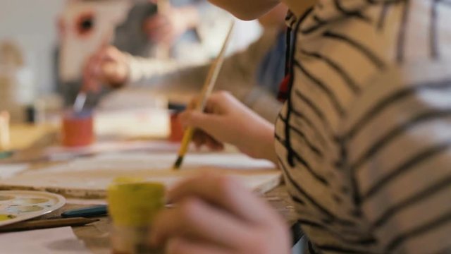 Close up hands of a child holding a brush and paints