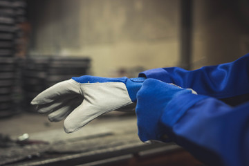 Worker getting on a pair of protection gloves. - obrazy, fototapety, plakaty