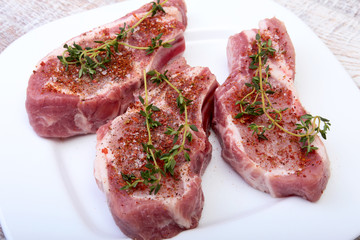 Raw pork chops, spices and rosemary on cutting board. Ready for cooking.