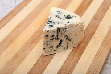 Plate with Tasty blue cheese on wooden table