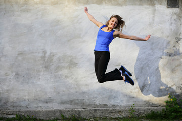 Happy smiling jump sport beautiful young woman on gray background