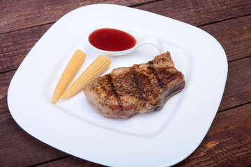 grilled pork chop with Cranberry sauce and Mini Corn cob preserved on plate on wooden board