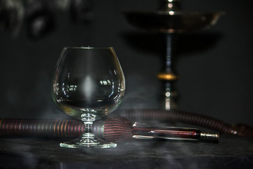 Heavy hookah smoke under a brandy glass on a gray background, hookah tube