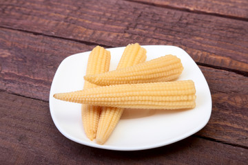 Mini Corn cob preserved on plate on wooden board.