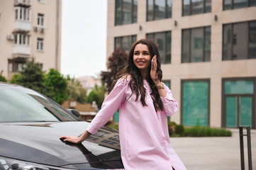 Fototapeta premium woman standing near car and calling by phone