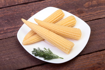 Mini Corn cob preserved on plate on wooden board.