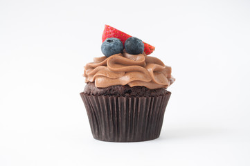 Chocolate cupcake with whipped chocolate cream, decorated fresh strawberry, blueberry on white background. Picture for a menu or a confectionery catalog.