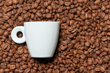Top view of small espresso coffee cup lying in coffee beans