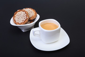 Classic espresso in white cup with homemade cake on black background. Selective focus.