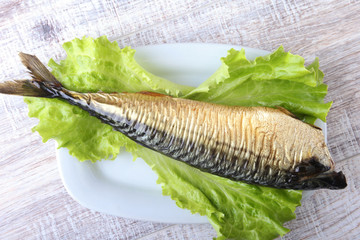 Smoked mackerele and lemon on green lettuce leaves on Wooden cutting board isolated on white...