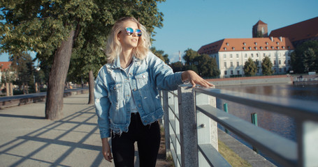 Young fashion woman in a city in Europe. Happy stylish girl in sunglasses enjoying summer.