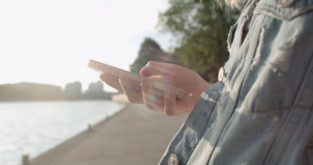 Close up of young female hands using phone, outdoors.