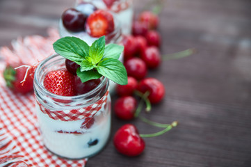 yogurt with Cherry and strawberries, square. Berries of blueberries and strawberries are scattered on the table.