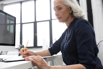 Mature business woman making notes on a piece of paper