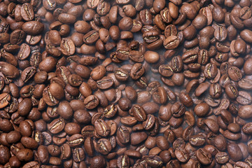 Roasted brown coffee beans with smoke, top view background