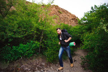 Traveler man walking with backpack in rocky mountains. Travel concept.
