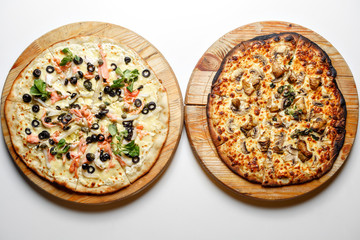 Burnt and normal. Two pizza with tomatoes, salmon, mushroom, pepperoni on wooden rustic background top view