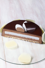 Contemporary Chocolate Coconut Mousse Cake (inside), on transparent glass board, on white wooden background.