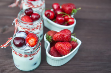 yogurt with Cherry and strawberries, square. Berries of blueberries and strawberries are scattered on the table.
