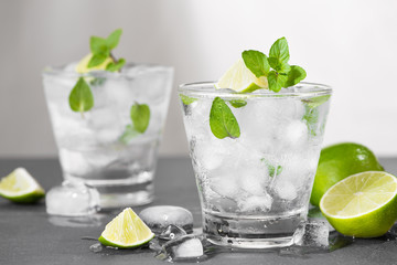 Mojito cocktail with lime and mint in glass on a grey stone background