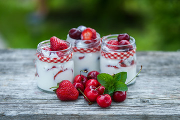 yogurt with Cherry and strawberries, square. Berries of blueberries and strawberries are scattered on the table.