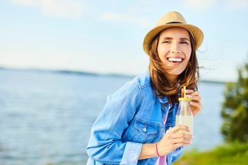 Joyful woman having fun drinking lemonade outdoors - obrazy, fototapety, plakaty