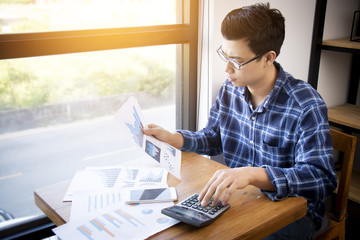 Business accounting people, saving, finance and economy concept. Serious Asian businessman using calculator for calculations documents , charts and graphs. Asia male model in his 30s