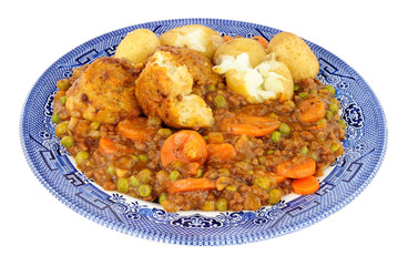 Minced beef stew with dumplings and new potatoes on a blue patterned plate isolated on a white...