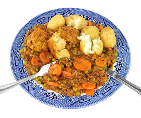 Minced beef stew with dumplings and new potatoes on a blue patterned plate isolated on a white background
