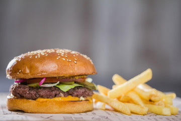 A large tasty burger with potatoes on the table
